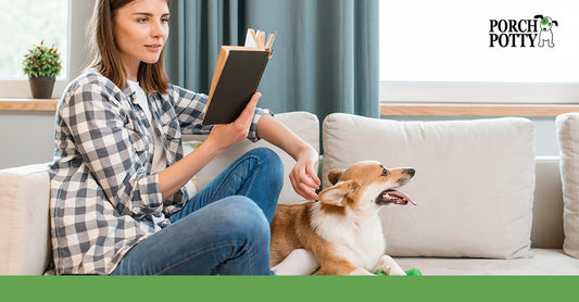 A woman reads a book while petting her puppy