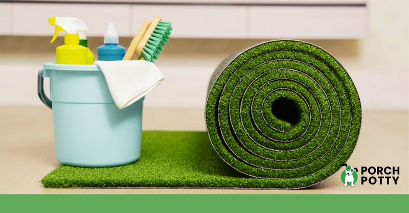 Rolled artificial grass beside a bucket of cleaning supplies on synthetic turf.